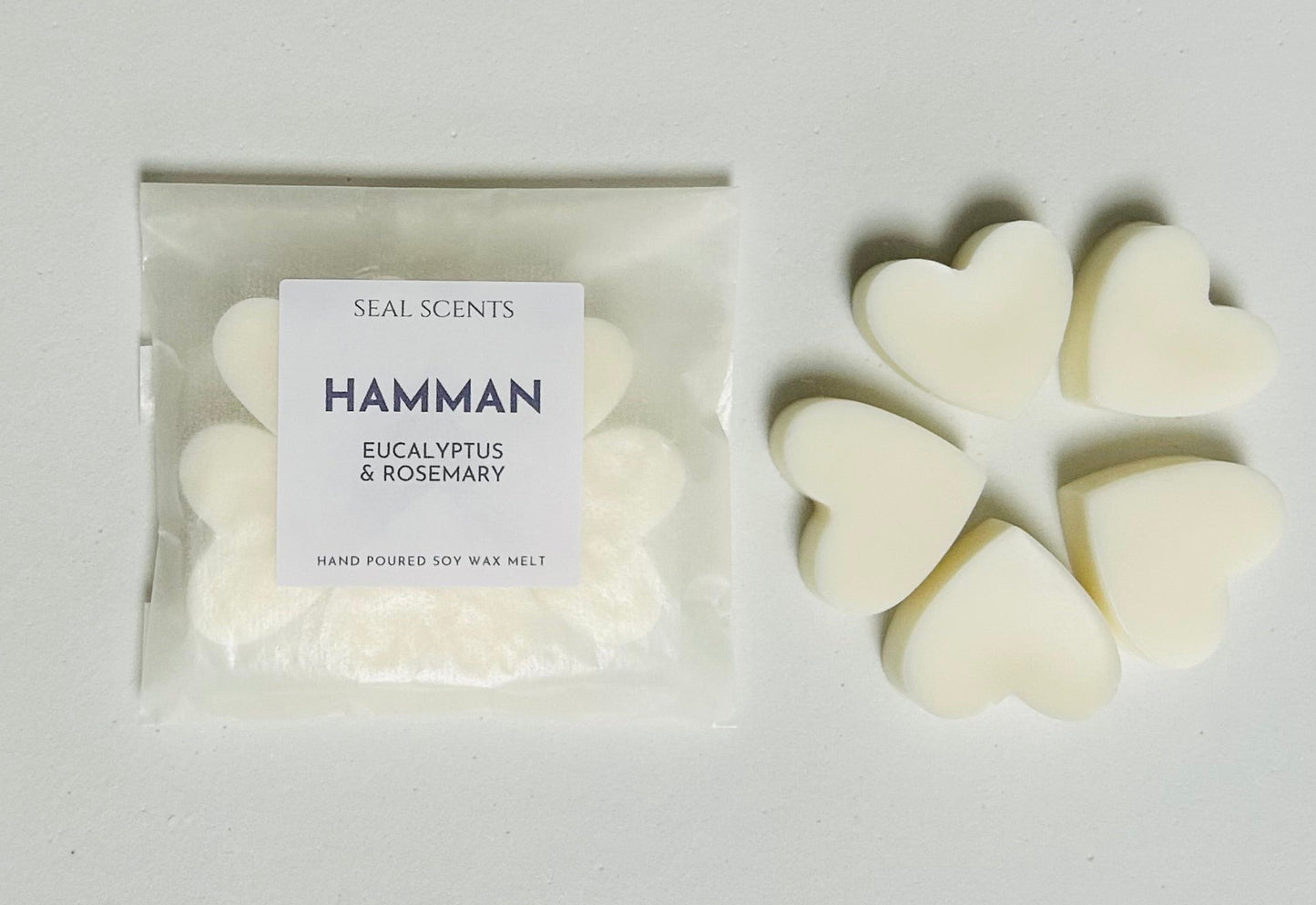 Heart-shaped white wax melts with a 'Hamman' label on a light gray background